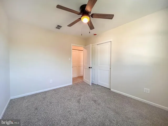 an empty room with closet and chandelier fan