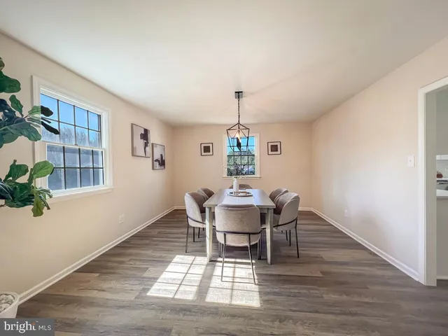 a dining room with wooden floor a chandelier a wooden table and chairs