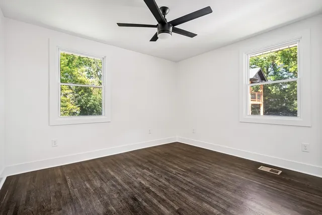 a view of empty room with wooden floor and fan