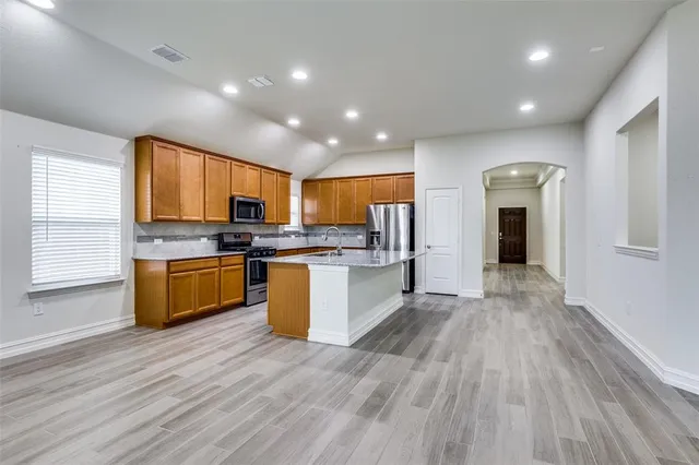 a kitchen with stainless steel appliances granite countertop a stove cabinets and wooden floor
