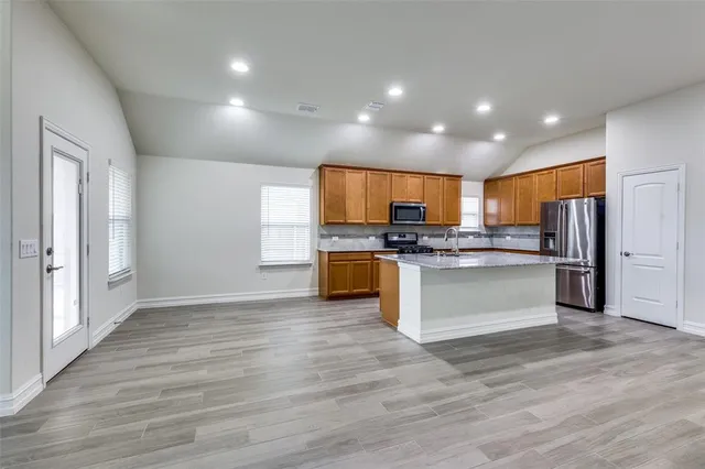 a kitchen with stainless steel appliances kitchen island granite countertop a stove and a refrigerator