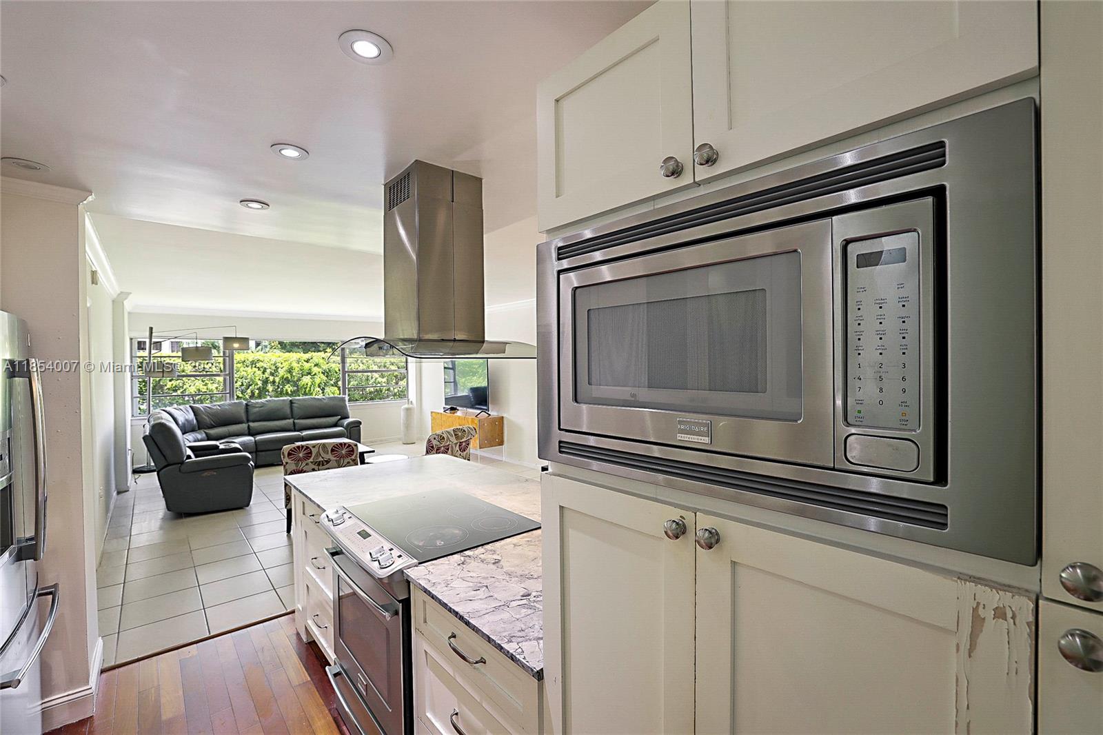 1700 Northeast 105th Street, Unit 203 Miami Shores, FL 33138 - Photo 13 of 45 a kitchen with stainless steel appliances granite countertop a stove a sink and a microwave