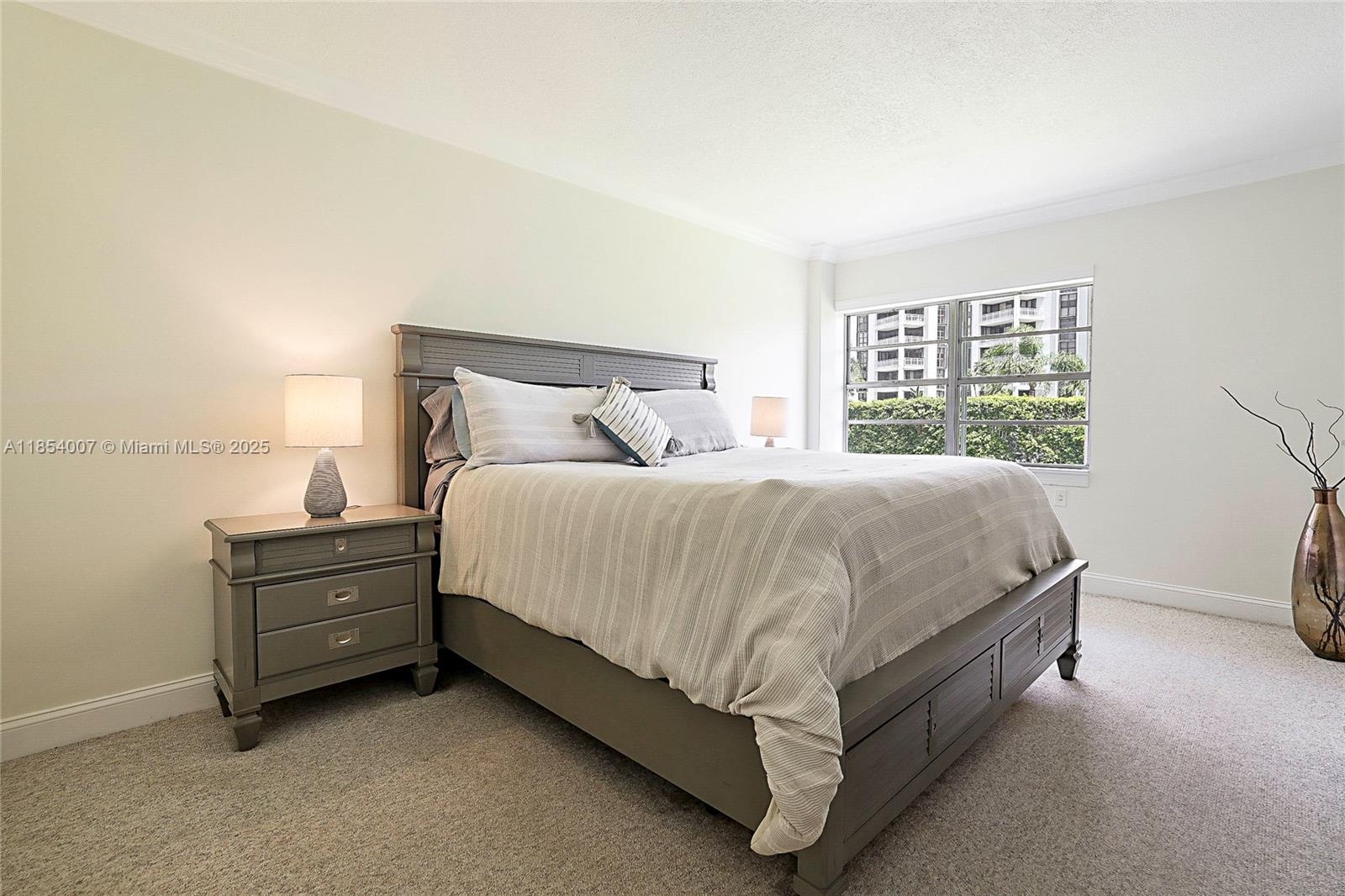 1700 Northeast 105th Street, Unit 203 Miami Shores, FL 33138 - Photo 17 of 45 a bed sitting in a bedroom next to a window