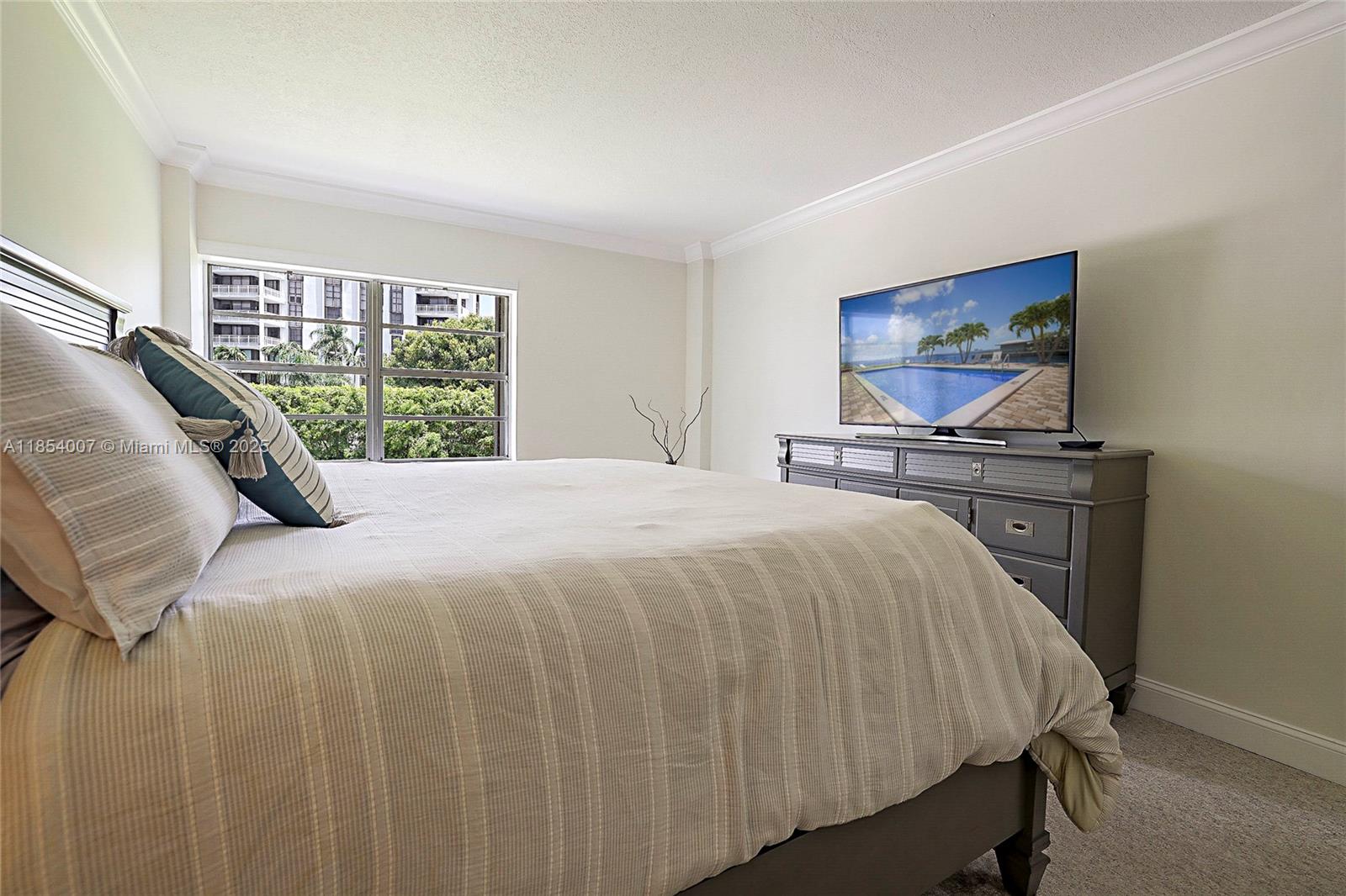 1700 Northeast 105th Street, Unit 203 Miami Shores, FL 33138 - Photo 18 of 45 a bed sitting in a bedroom next to a window