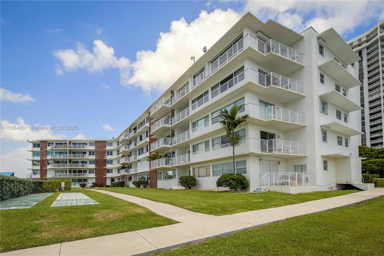 1700 Northeast 105th Street, Unit 203 Miami Shores, FL 33138 - Photo 36 of 45 a view of a tall building next to a big yard