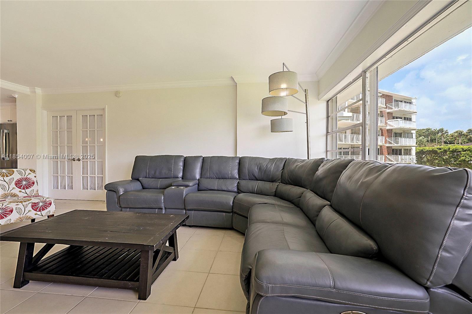 1700 Northeast 105th Street, Unit 203 Miami Shores, FL 33138 - Photo 4 of 45 a living room with furniture a table and a large window