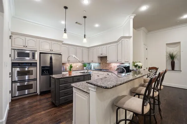 a kitchen with stainless steel appliances granite countertop a stove refrigerator a dining table and chairs with wooden floor