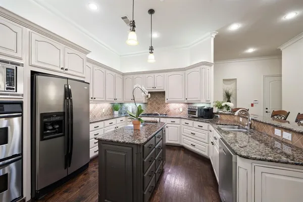 a kitchen with stainless steel appliances granite countertop a sink refrigerator and cabinets