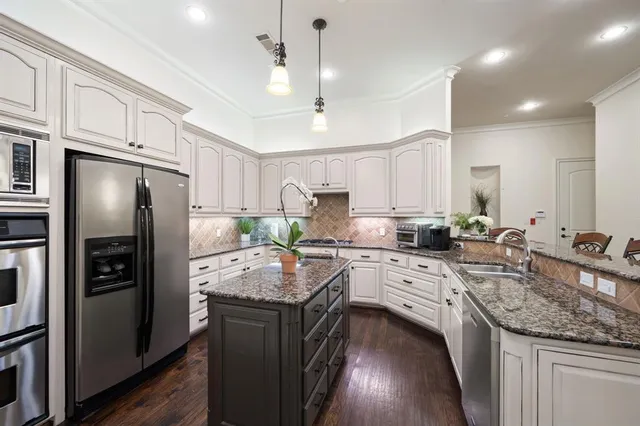 a kitchen with stainless steel appliances granite countertop a sink refrigerator and cabinets