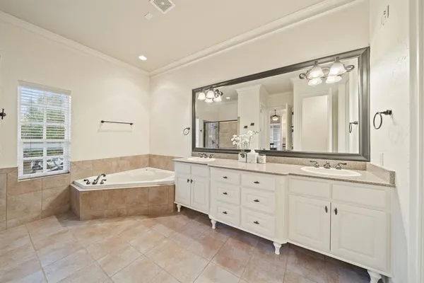 a spacious bathroom with a double vanity sink a mirror and a bathtub