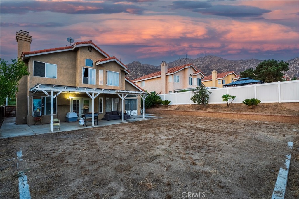 21329 Tennyson Road Moreno Valley, CA 92557 - Photo 29 of 32 a view of a white house with a yard and large tree