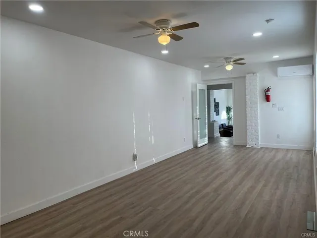an empty room with wooden floor and a ceiling fan