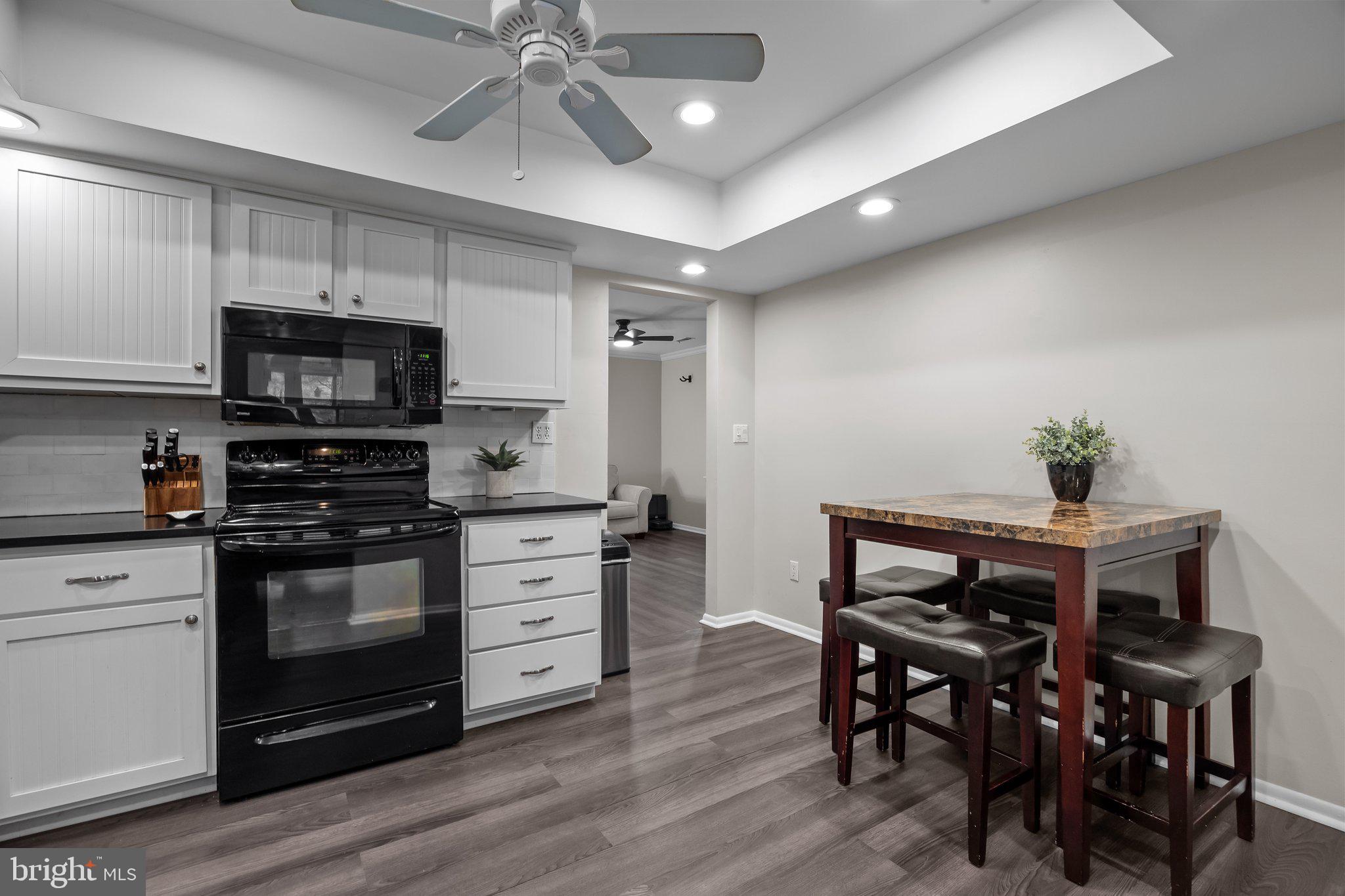 609 Hampton Court Doylestown, PA 18901 - Photo 14 of 41 a kitchen with stainless steel appliances a stove a microwave a dining table and chairs with wooden floor