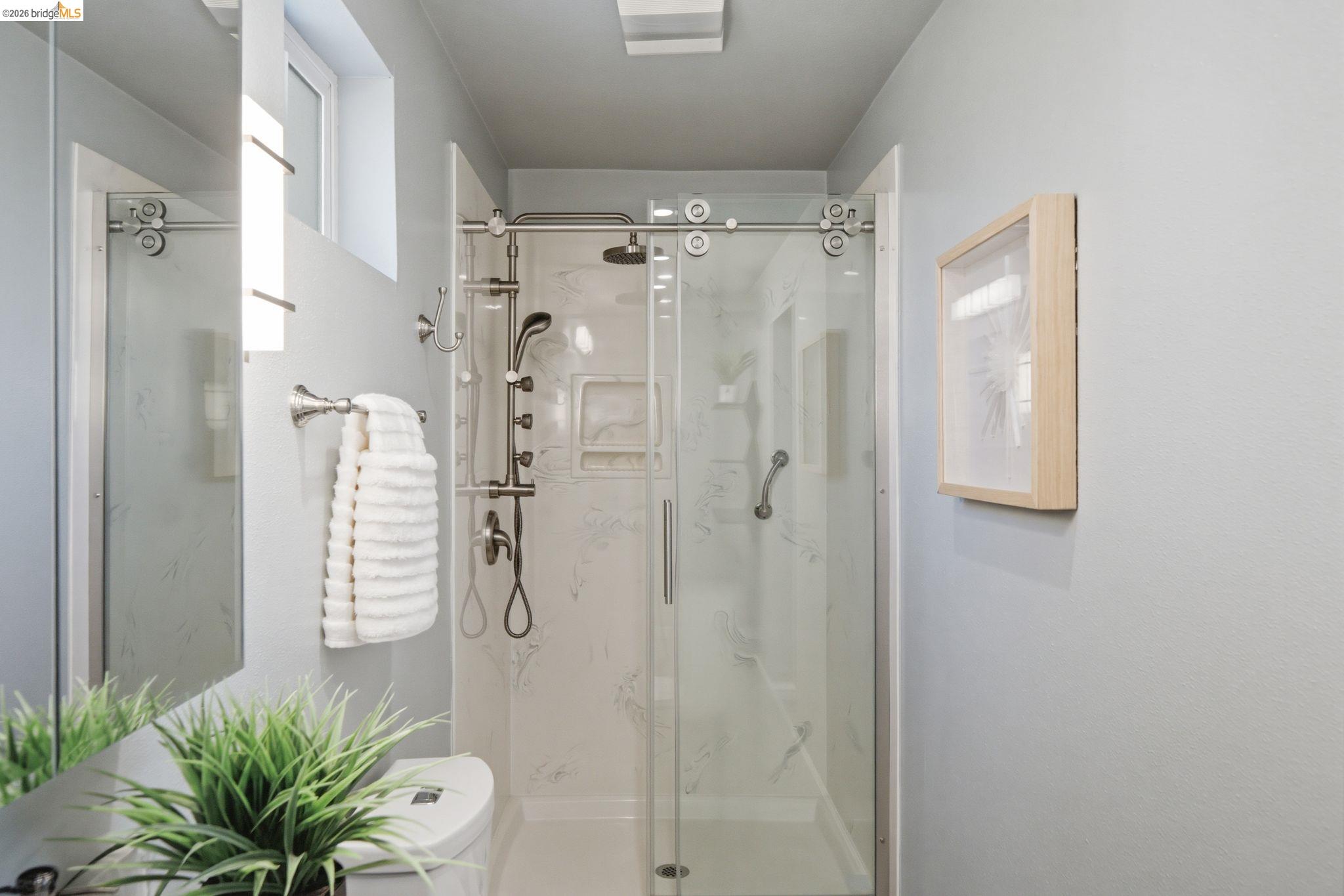 11133 Golf Links Road Oakland, CA 94605 - Photo 40 of 57 Walk-in shower with sliding glass door, multi-function shower system, integrated shelving, and support bar