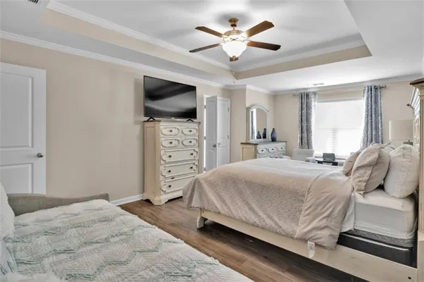 a bedroom with a large bed a flat tv screen and a dresser