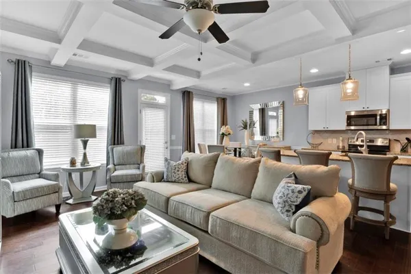 a living room with furniture kitchen view and a large window