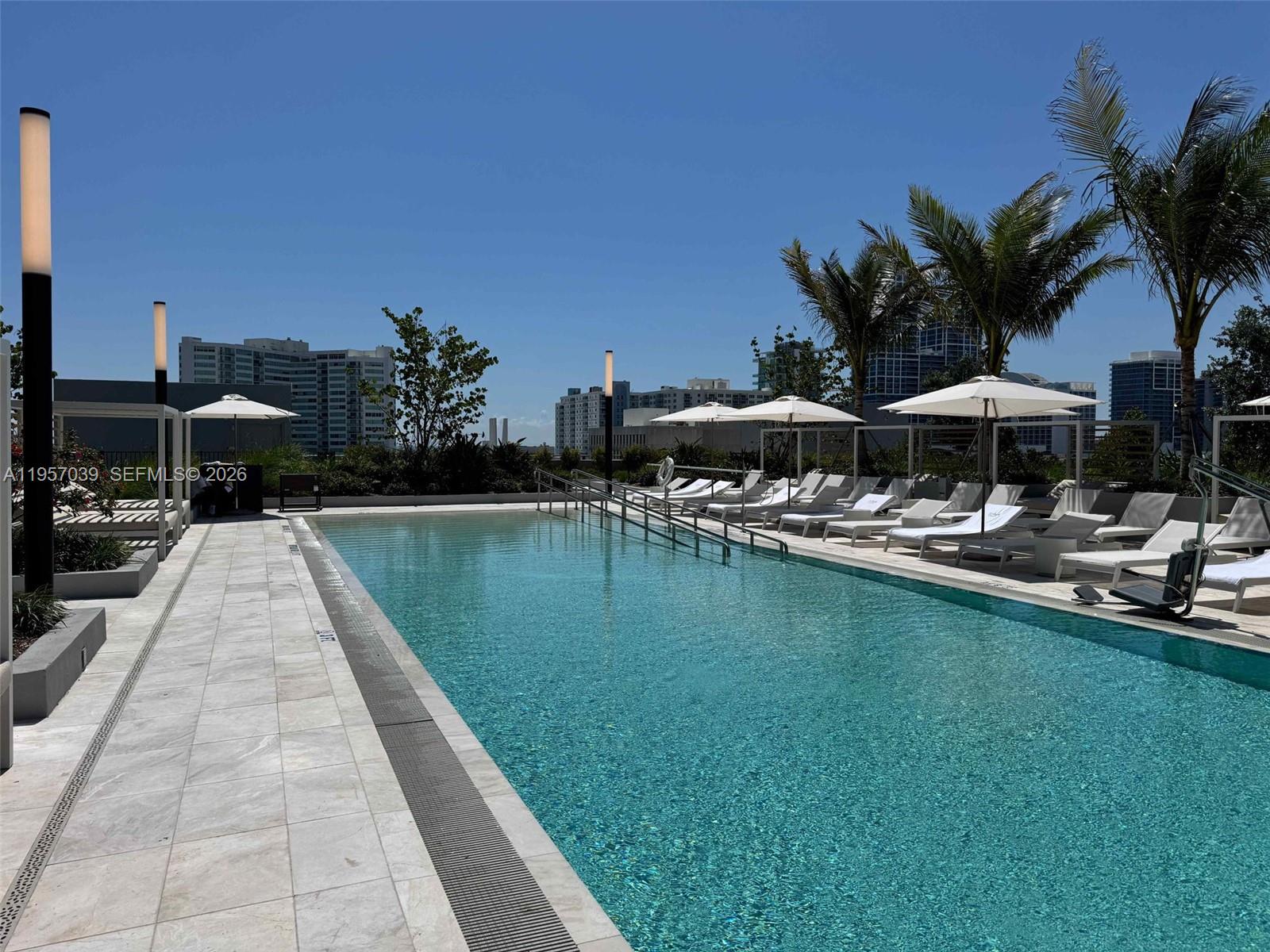 580 72nd Street, Unit 808 Miami Beach, FL 33141 - Photo 28 of 29 a view of swimming pool with outdoor seating and a garden