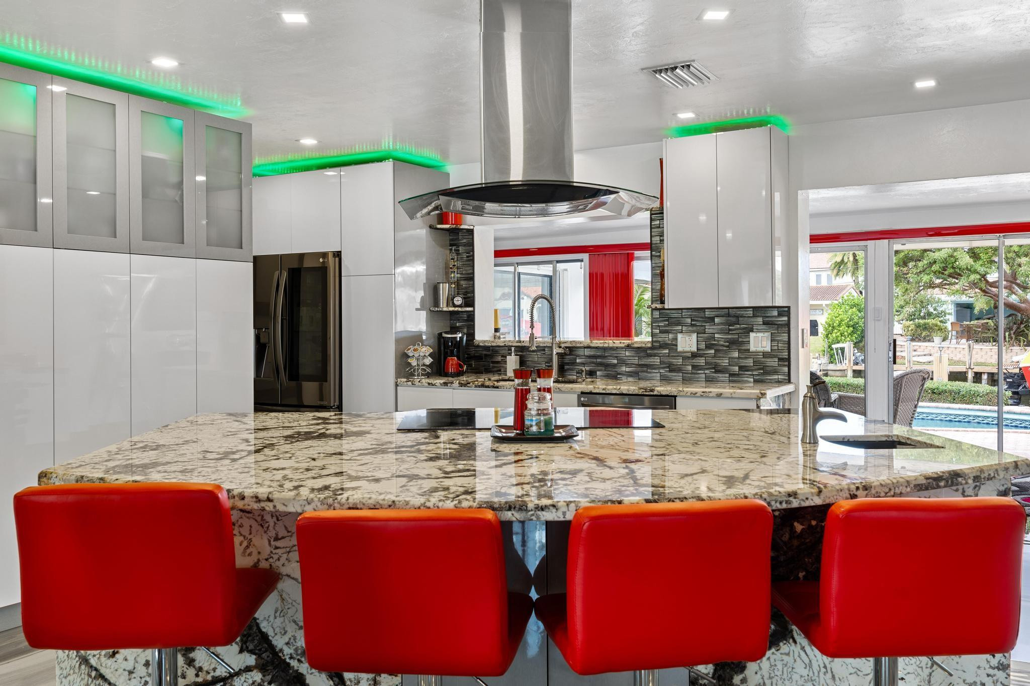 2531 Northeast 47th Street Lighthouse Point, FL 33064 - Photo 13 of 52 a kitchen with stainless steel appliances granite countertop a kitchen island a stove a refrigerator and a dining table