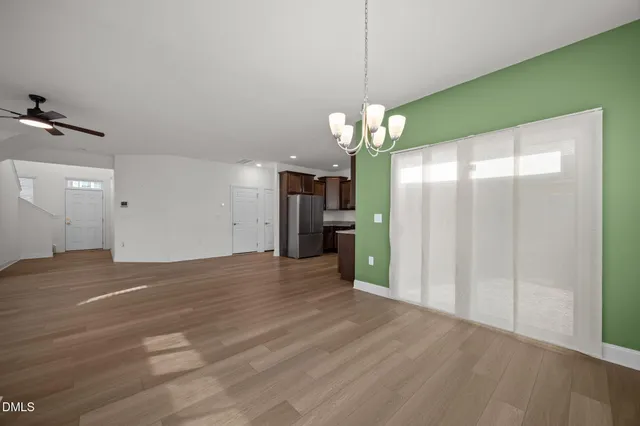 a view of a livingroom with a chandelier wooden floor and a kitchen