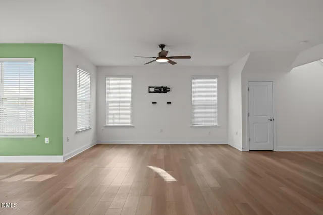 a view of an empty room with window and wooden floor