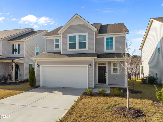 a view of a white house with large windows next to road