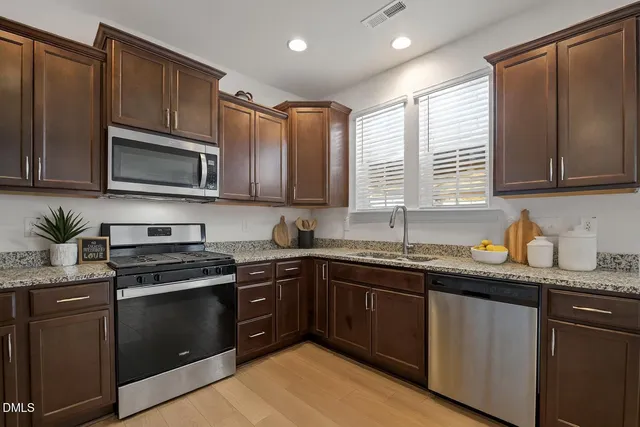 a kitchen with stainless steel appliances granite countertop wooden cabinets a stove a sink and dishwasher