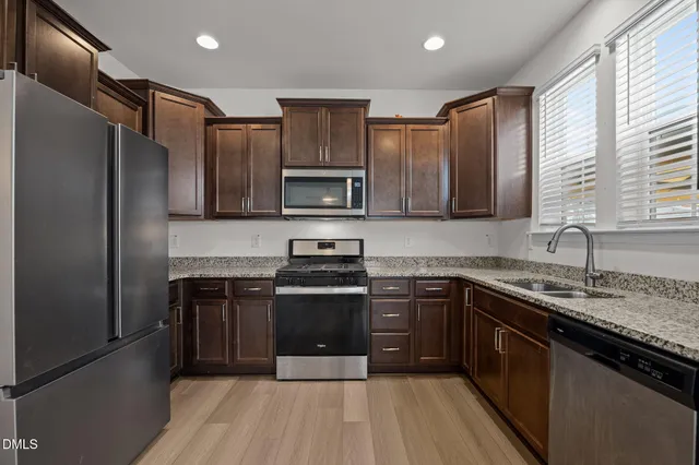 a kitchen with stainless steel appliances granite countertop a stove a sink dishwasher a refrigerator and a microwave oven