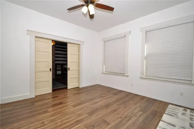 an empty room with wooden floor closet and windows