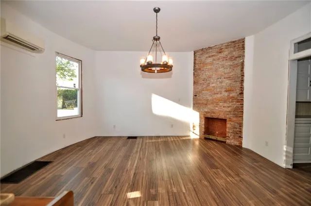 a view of empty room with wooden floor and fireplace