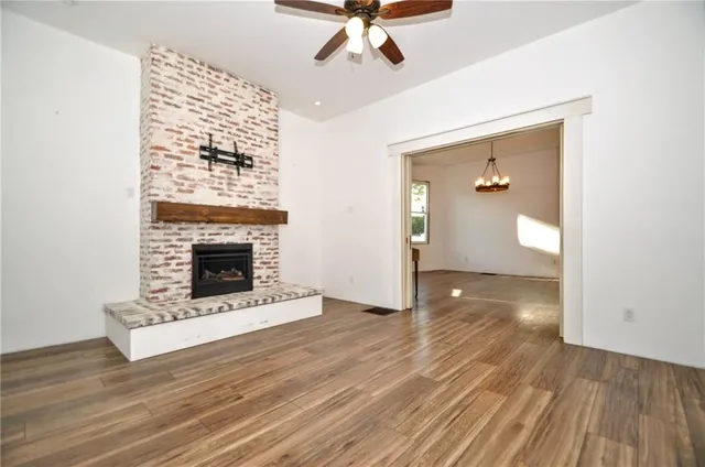 a view of a livingroom with a fireplace a chandelier and wooden floor