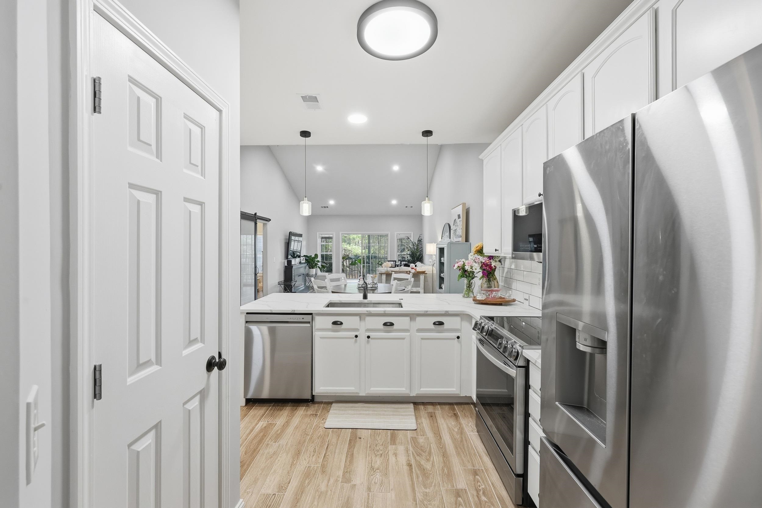 5810 Longwood Drive, Unit 303 Murrells Inlet, SC 29576 - Photo 26 of 27 Kitchen with stainless steel appliances, white cabinets, open floor plan, a peninsula, and light wood finished floors