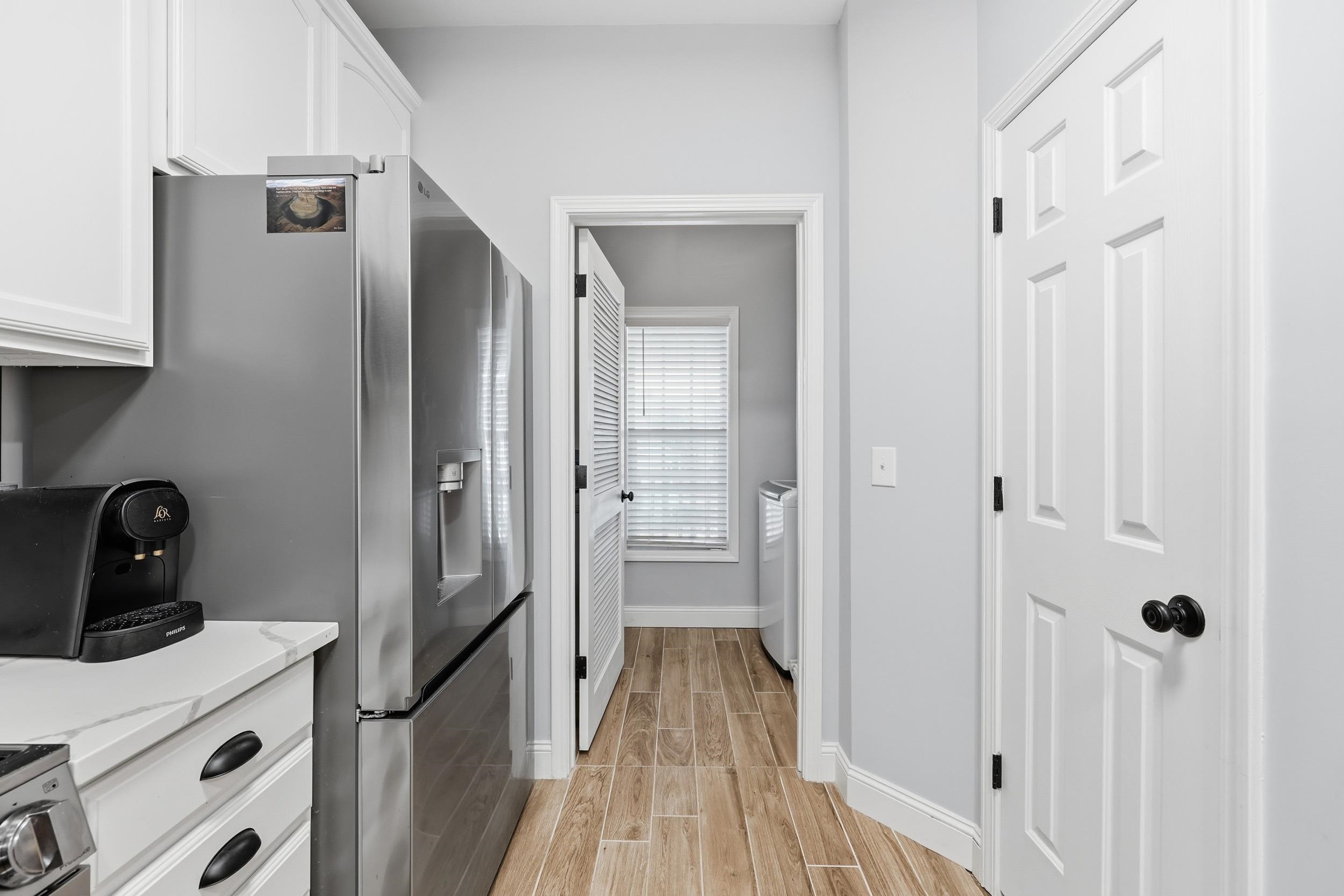 5810 Longwood Drive, Unit 303 Murrells Inlet, SC 29576 - Photo 8 of 27 Kitchen featuring white cabinetry, wood finish floors, light stone counters, and washing machine and dryer