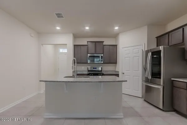 a kitchen with stainless steel appliances granite countertop a refrigerator a stove a sink and a microwave