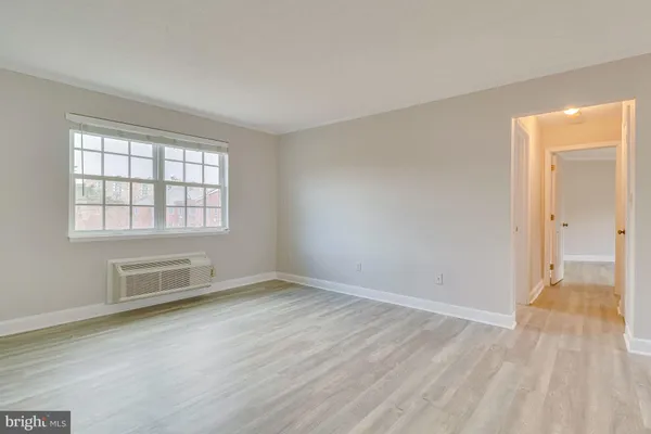 an empty room with wooden floor cabinet and windows