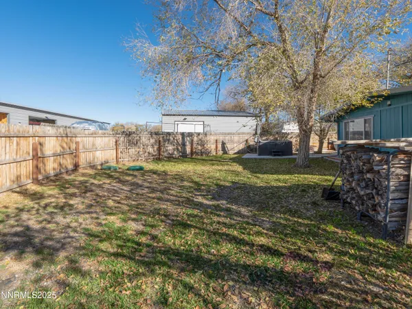a view of a backyard with wooden fence and a large tree