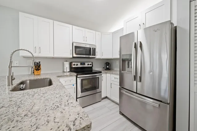 a kitchen with stainless steel appliances granite countertop a refrigerator sink and stove