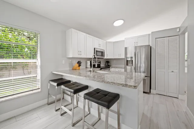 a kitchen with stainless steel appliances granite countertop a stove a refrigerator a sink a stove and island with wooden floor