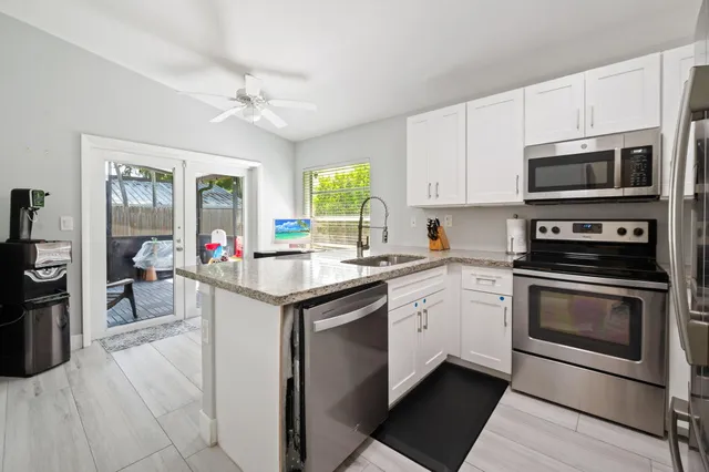 a kitchen with stainless steel appliances granite countertop a stove top oven a sink dishwasher and a microwave oven with cabinets