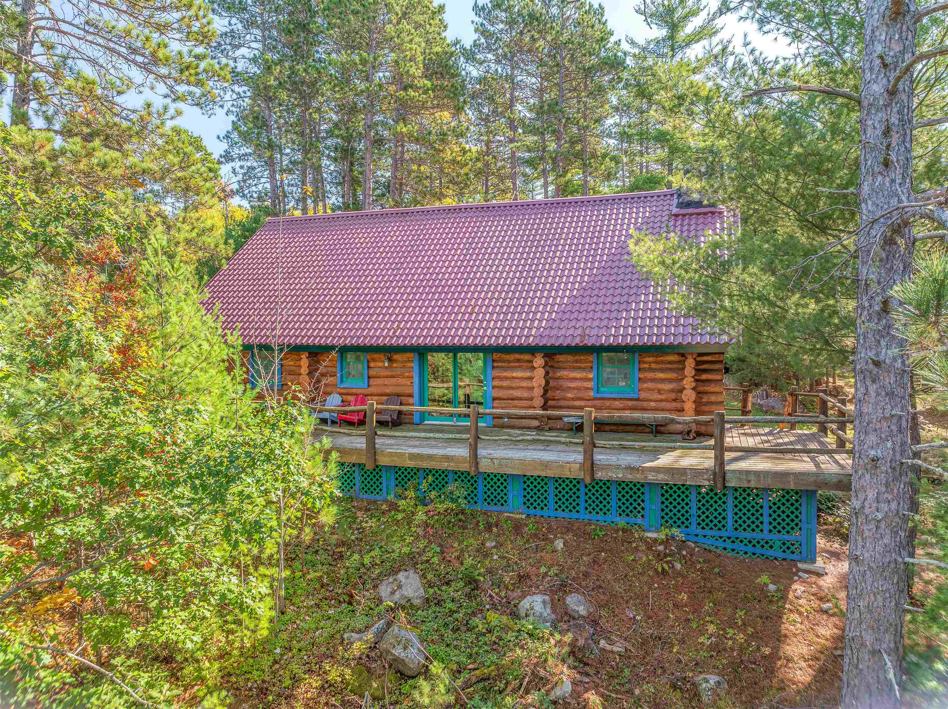 Rear view of house featuring a deck, log siding, and a tile roof