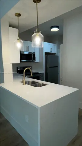 a kitchen with kitchen island a sink and a chandelier