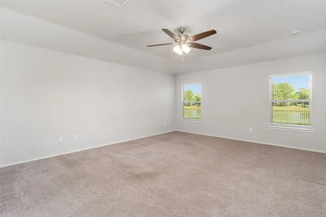 an empty room with windows and fan