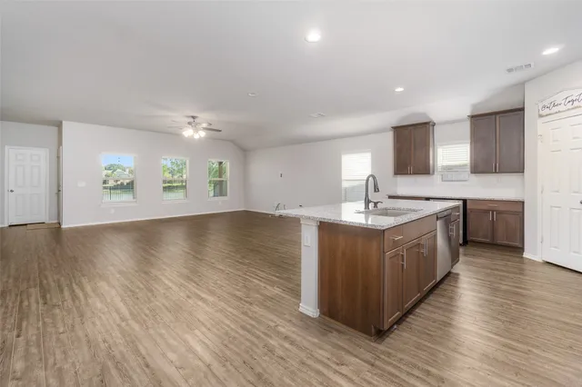 a large kitchen with a large counter top a sink stainless steel appliances and cabinets