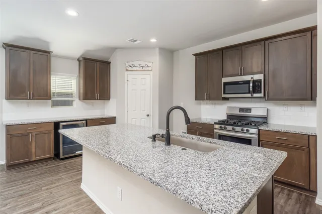a kitchen with granite countertop a stove microwave and sink