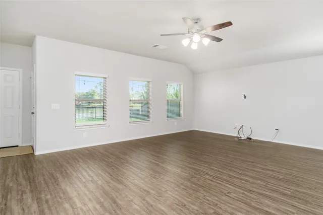 a view of an empty room with window and wooden floor