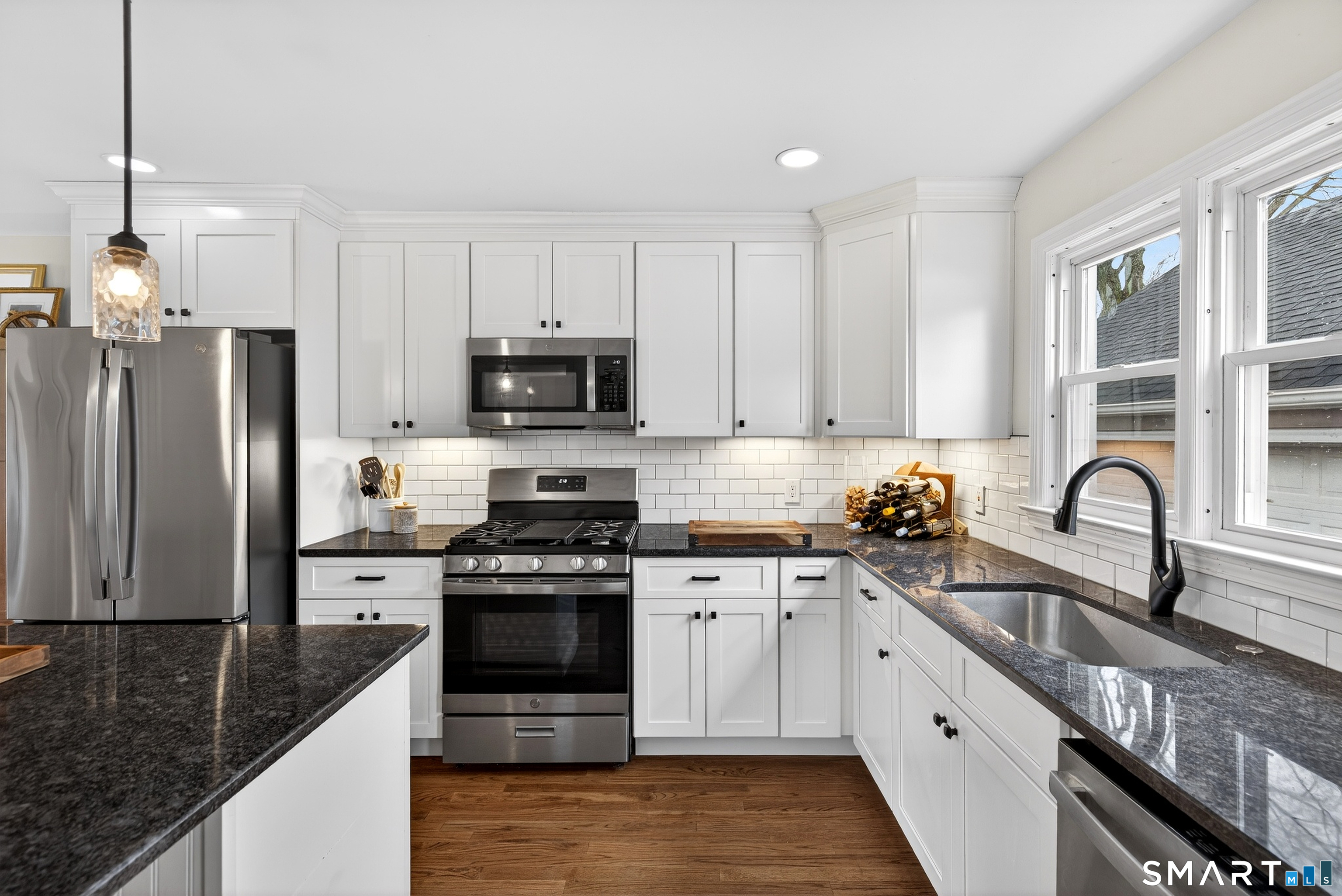 45 Walnut Street Milford, CT 06461 - Photo 15 of 39 a kitchen with stainless steel appliances granite countertop a stove a sink dishwasher a refrigerator and white cabinets with wooden floor