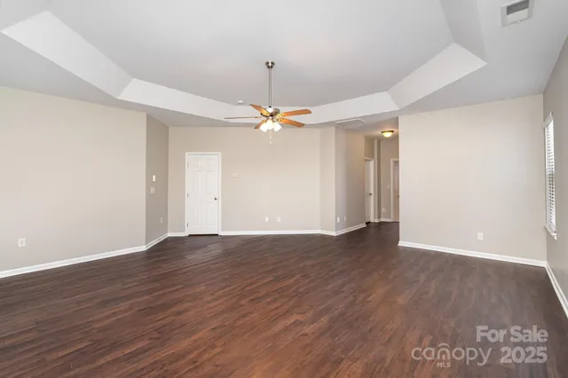 an empty room with wooden floor fan and windows