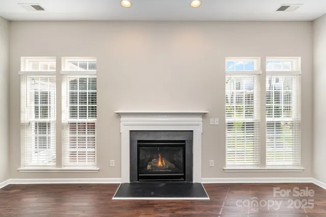 a living room with a fireplace a window and a wooden floor