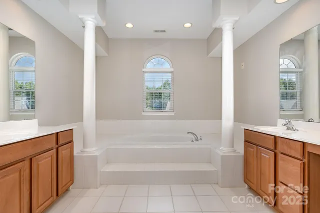 a spacious bathroom with a tub sink and mirror