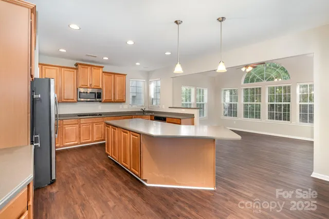a large kitchen with kitchen island a large counter top space a sink stainless steel appliances and cabinets
