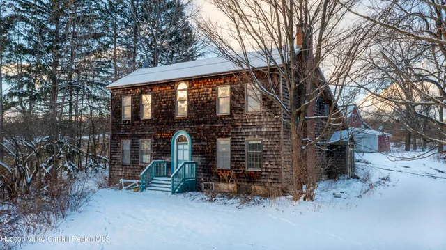 a small barn with a table and chairs under an umbrella